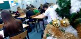Uczniowie piszą w klasie, choinka w tle.