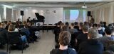 Widok na widownię młodzieży z perspektywy sali konferencyjnej. Pianista przy fortepianie.