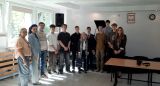 Grupowe zdjęcie młodzieży, nauczycieli i prelegentów w sali wykładowej.