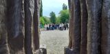 Perspektywa z wnętrza betonowego pomnika na idącą w oddali grupę młodzieży szkolnej na brukowanym placu.