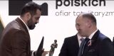 Dwaj mężczyźni wymieniają nagrody podczas uroczystości.