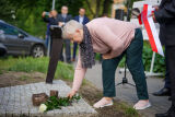 Kobieta składa wieniec na pamiątkowej tablicy.