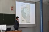 Prezentacja mapy w sali wykładowej. Mężczyzna mówi do słuchaczy.