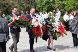 Ludzie niosą wieńce w trakcie uroczystości upamiętniającej.