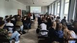 Widok z tyłu sali na uczniów oglądających prezentację historyczną z archiwalnym zdjęciem miejskiego placu.