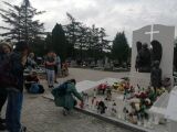 Uczczenie pamięci przy grobie z płonącymi zniczami i kwiatami.